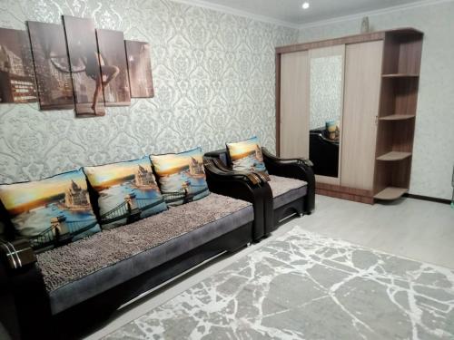 una sala de estar con 2 sofás negros y un espejo en Квартиры, en Shchūchīnsk