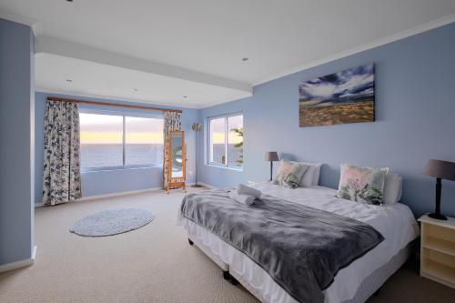 a bedroom with a large bed and a large window at Bahari Villa in Simonʼs Town