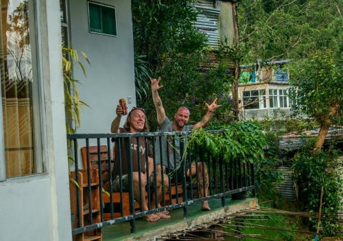 a man and woman sitting on a balcony with their hands in the air at Water Side Residence in Adams Peak