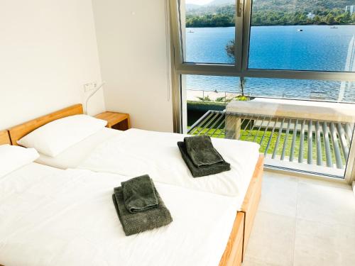 two beds with towels on them in a room with a large window at Chalet PAM - 1 line s'Albufera lake - near by beach in Alcudia
