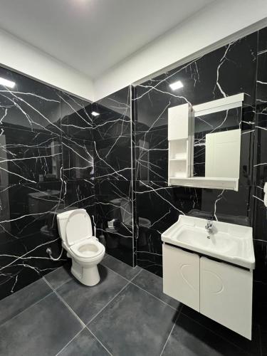 Harmony Apartments في سارنده: حمام من البلاط الأسود مع مرحاض ومغسلة