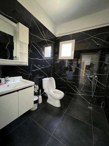 a black bathroom with a toilet and a sink at Harmony Apartments in Sarandë