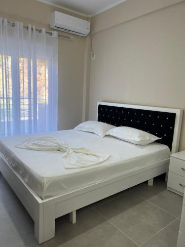 una camera da letto con un grande letto con lenzuola e cuscini bianchi di Harmony Apartments a Sarandë