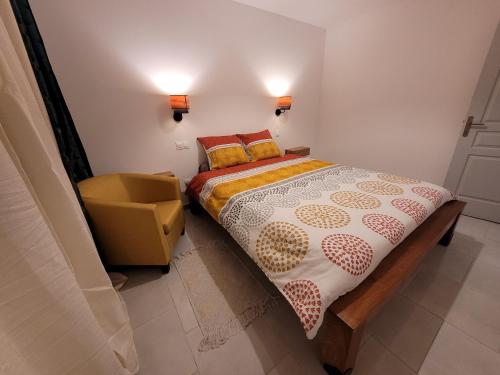 a small bedroom with a bed and a chair at Le Refuge d'Heva in Salazie