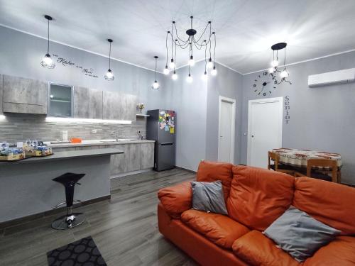 a living room with an orange couch and a kitchen at The Junior House - Casa Vacanza in Lauria Inferiore