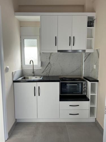 a white kitchen with a sink and a microwave at Harmony Apartments in Sarandë