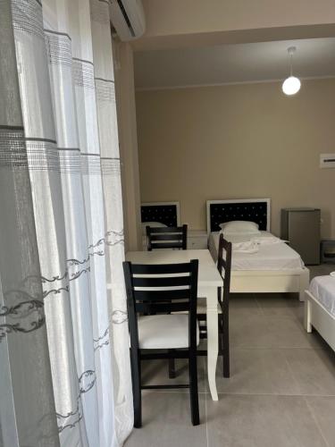 a room with a table and chairs and a bed at Harmony Apartments in Sarandë
