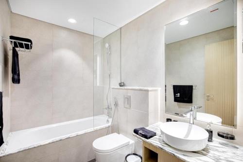 杜拜的住宿－Paramount Midtown Deluxe 1 BR Apartment with Full Burj-Khalifa View，浴室配有盥洗盆、卫生间和浴缸。