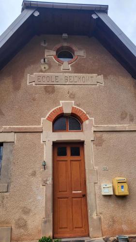 - un bâtiment avec une porte et un panneau dans l'établissement ECOLE de BELMONT, à Le Haut-du-Them