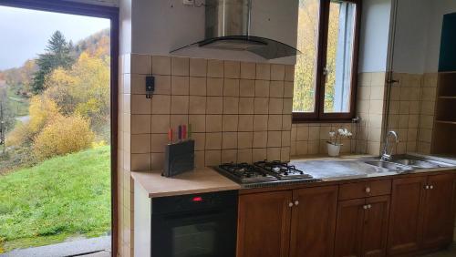 uma cozinha com fogão forno superior ao lado de uma janela em ECOLE de BELMONT em Le Haut-du-Them