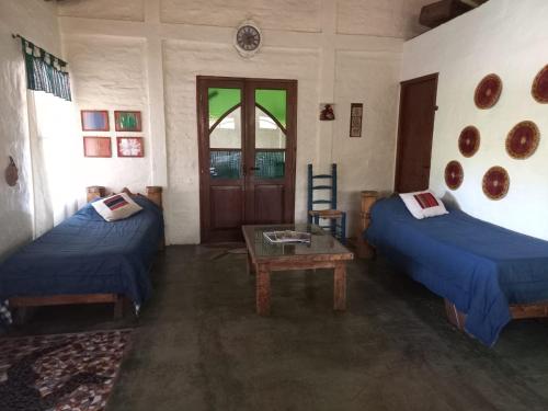 Habitación con 2 camas, mesa y puerta en Cazasanta en Mendoza