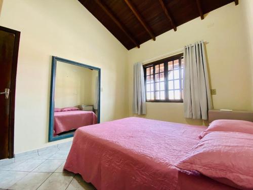1 dormitorio con cama rosa y espejo en Paraíso em Bombas rua Rouxinol, en Bombinhas
