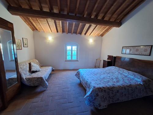 ein Schlafzimmer mit einem Bett, einem Sofa und einem Fenster in der Unterkunft Casa Daria, Armonia del Passato nel rispetto della natura in Donoratico