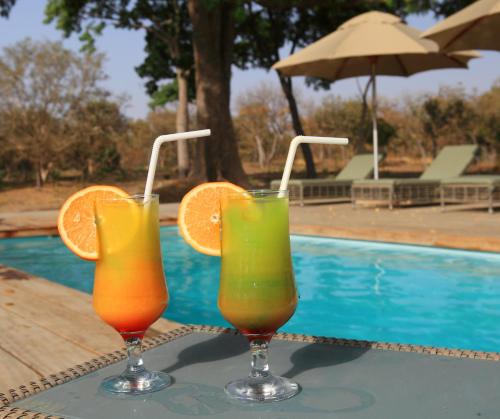 two drinks sitting on a table next to a pool at Fathala Wildlife Reserve in Toubakouta