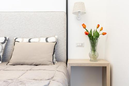 1 dormitorio con 1 cama con un jarrón de flores sobre una mesa en la dimora di Cornelia en Sorrento