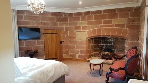 a bedroom with a brick wall with a fireplace at Dalston Hall in Carlisle