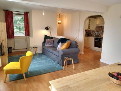 a living room with a blue couch and a yellow chair at Gorgeous private apartment mesmerising sea views in Teignmouth