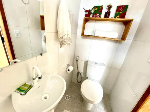 a white bathroom with a toilet and a sink at Vila Vasconcelos in Itacaré