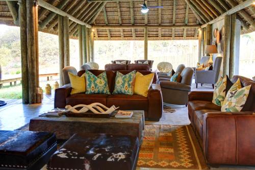 a living room with brown leather couches and chairs at Fathala Wildlife Reserve in Toubakouta