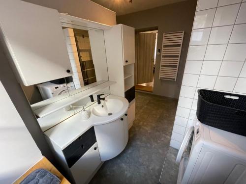 a white bathroom with a sink and a mirror at Gîte À l'aigle de sable in Kintzheim