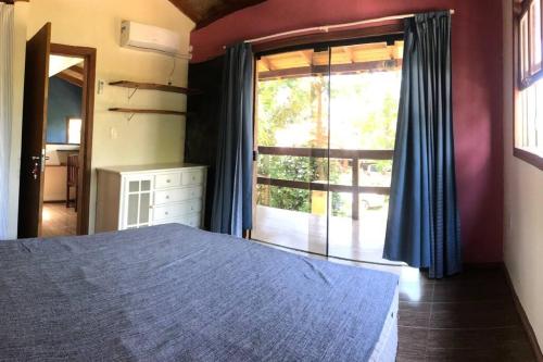 1 dormitorio con cama y ventana grande en Nova Casa Laranjeiras, en Garopaba