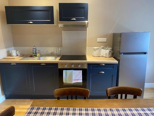 a kitchen with blue cabinets and a sink and a refrigerator at Hostellerie Alsacienne de Masevaux in Masevaux