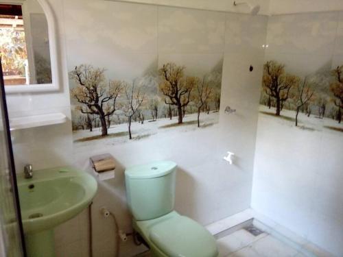 łazienka z toaletą i umywalką z drzewami na ścianie w obiekcie Yunal's Place w mieście Matara