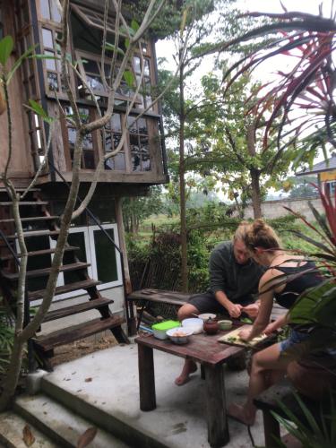 twee mensen zitten aan een picknicktafel in een tuin bij Baan Mali Lampang Homestay in Lampang