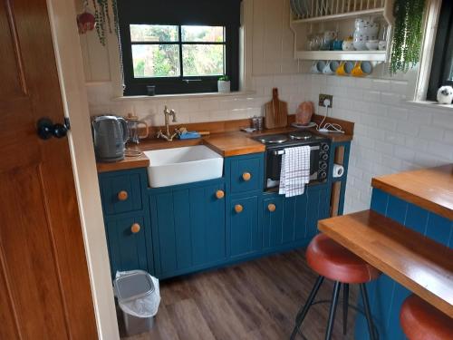 cocina azul con fregadero y fogones en Delightful Shepherds Hut en Westport