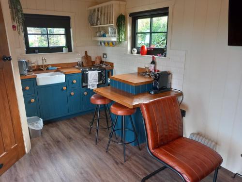 kuchnia z niebieskimi szafkami, blatem i stołkiem w obiekcie Delightful Shepherds Hut w mieście Westport