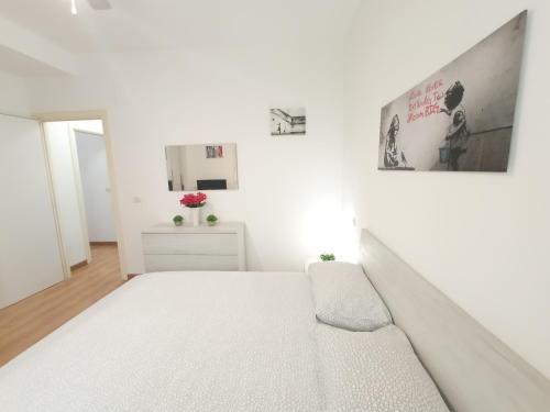 a white bedroom with a white bed and a mirror at Dietro Piazza in Ascoli Piceno