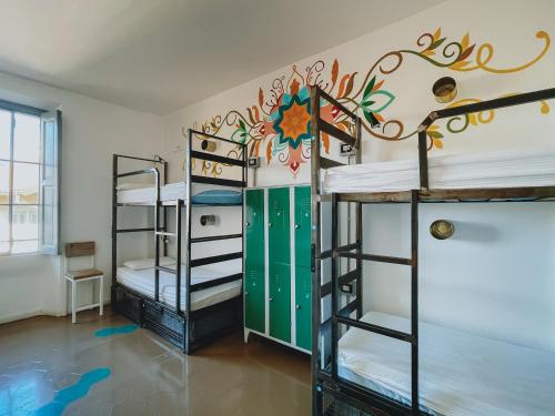 a room with three bunk beds and a mural on the wall at Madama Hostel & Bistrot in Milan