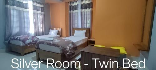 a bedroom with two beds and a window at Monshing Homestay - Elevate your travel experience in Bomdila