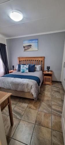a bedroom with a bed with blue sheets and two tables at Clarens, Paddocks 23 in Clarens