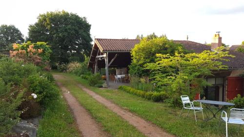 a dirt road leading to a house with a table and chairs at Clos de l'Arthonnet in Flavignac