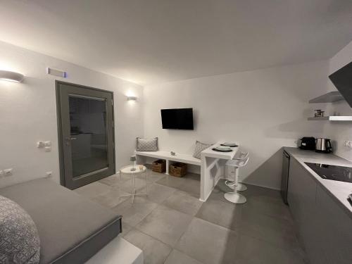 a small white kitchen with a desk and a television at Alexander Suites in Drios