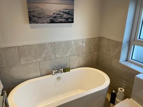 a bath tub in a bathroom with a picture on the wall at Private Room in Saintfield in Saintfield