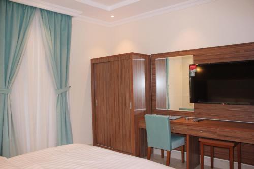 a hotel room with a desk and a television and a bed at التميز الراقي - الفيصلية in Jeddah