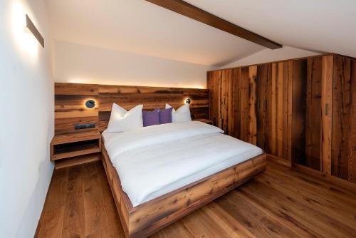 een slaapkamer met een bed met een houten muur bij Aromis in Termeno