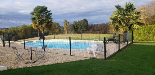 une clôture autour d'une piscine avec une table et des chaises dans l'établissement Gite au paradis, à Meyrals