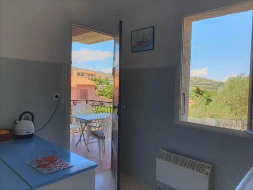 - une cuisine avec vue sur une table et une fenêtre dans l'établissement Banyuls vu d'en haut : appartement T3 spacieux, à Banyuls-sur-Mer