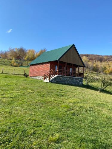 a red barn with a green roof in a field at Ethno village & resort Ćorić in Mojkovac