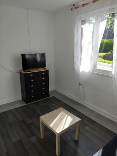 a living room with a table and a tv and window at Guern ,maison à la campagne in Guern