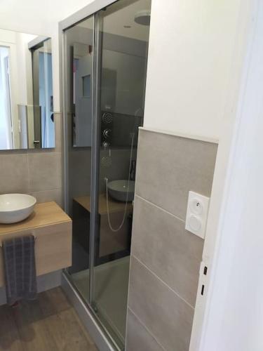 uma casa de banho com uma cabina de duche em vidro e um lavatório. em Guern ,maison à la campagne em Guern