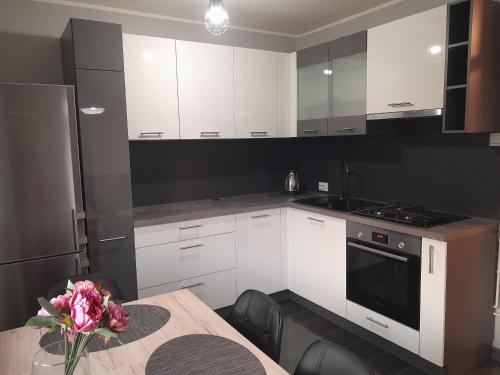 a kitchen with white cabinets and a table with a vase of flowers at Apartment Amalia in Varaždin