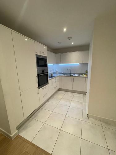 an empty kitchen with white cabinets and appliances at Amazing apartment moments away from the heart of London in London