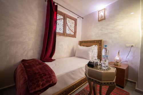 a bedroom with a bed and a table and a window at Riad Fes Elite in Fès