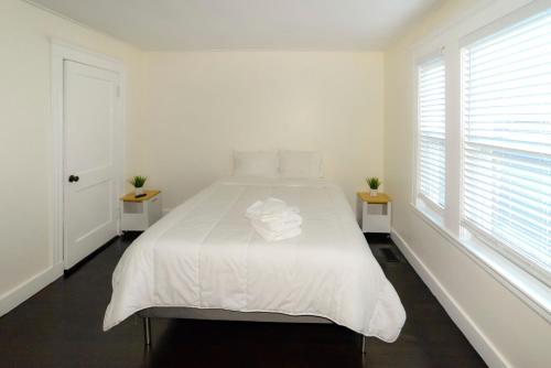 a white bedroom with a white bed with two windows at Modern Two Bedroom Condo - Boston in Stoneham