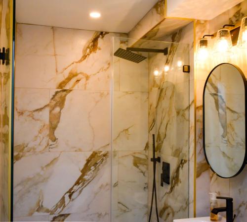 uma casa de banho com um chuveiro e um espelho. em Modern Two Bedroom Condo - Boston em Stoneham
