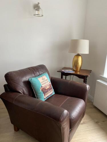 a brown leather couch with a blue pillow on it at Island town Apartment in Enniskillen